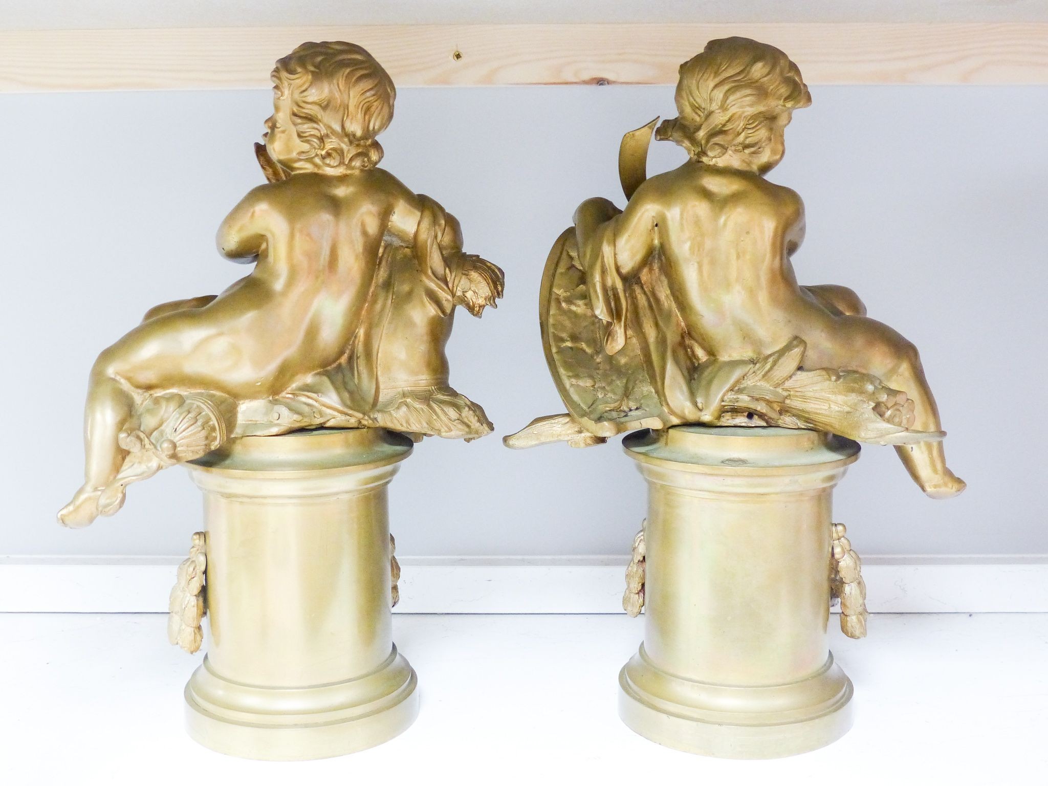 A pair of bronze figures of Cupid on circular pedestals, early 20th century, 42 cm high